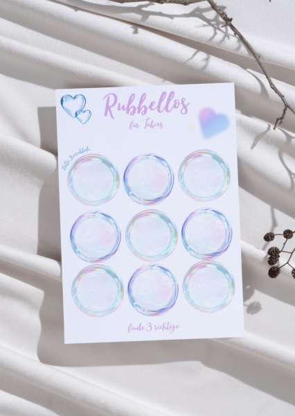 Rubbellos-Karte mit neun schimmernden Rubbelkreisen auf weißem Hintergrund, personalisiert mit Namen „Tobias“ – fotografiert auf Stoff mit Trockenblumen und Zweigen